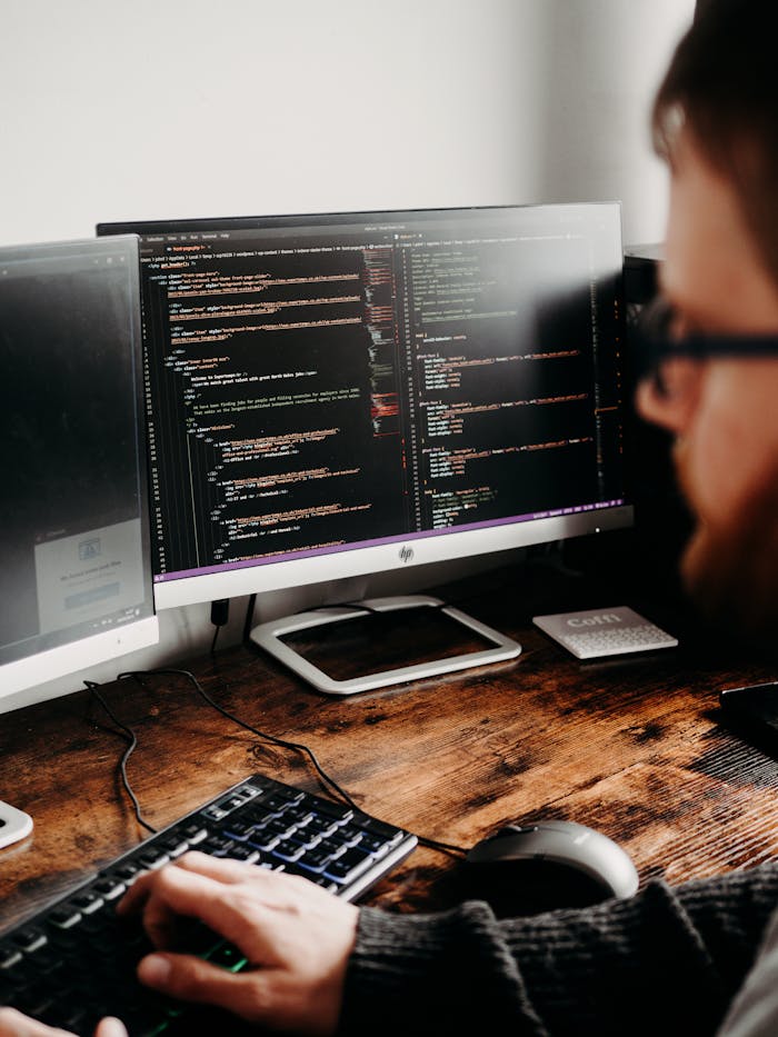 Crafting Captivating Headlines: Your awesome post title goes here Focused software developer at desk coding with multiple monitors in a modern workspace.
